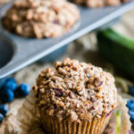 Zucchini Blueberry Muffins with Stresel Topping in wrapper with fresh blueberries