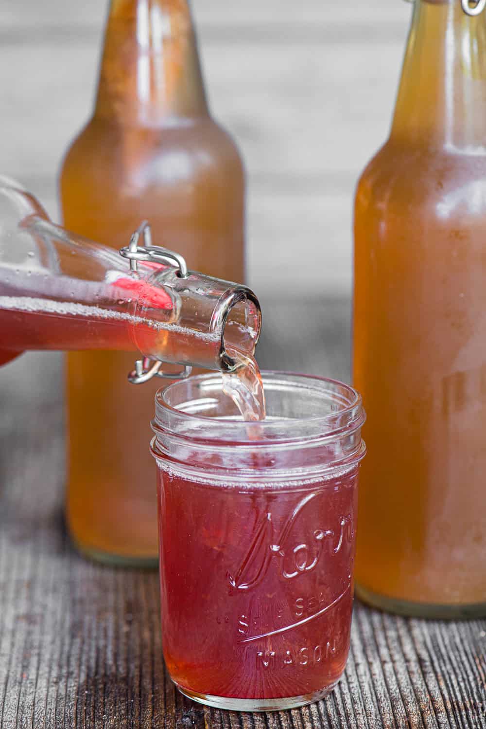 pouring flavored fermented tea into a mason jar