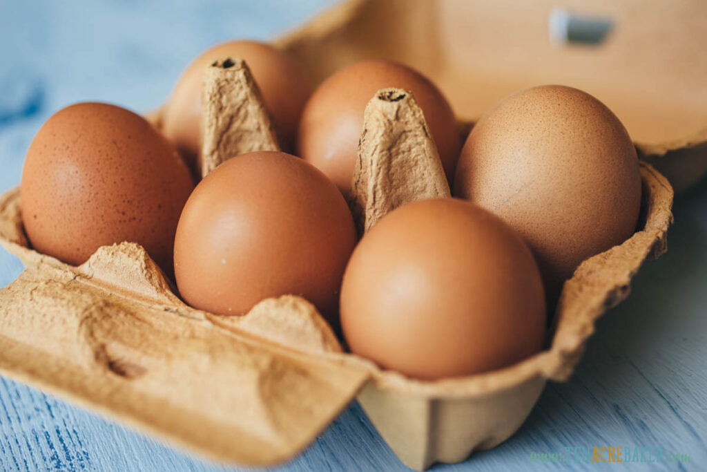Closeup view of eggs in carton box on wooden table. F